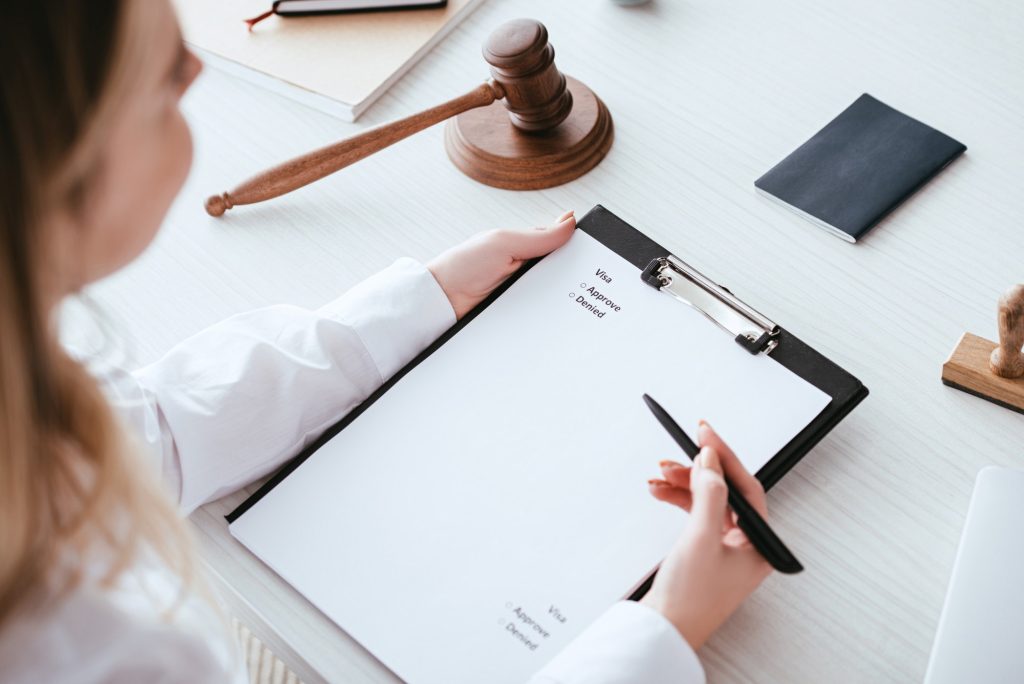 cropped view of woman holding clipboard with document near gavel