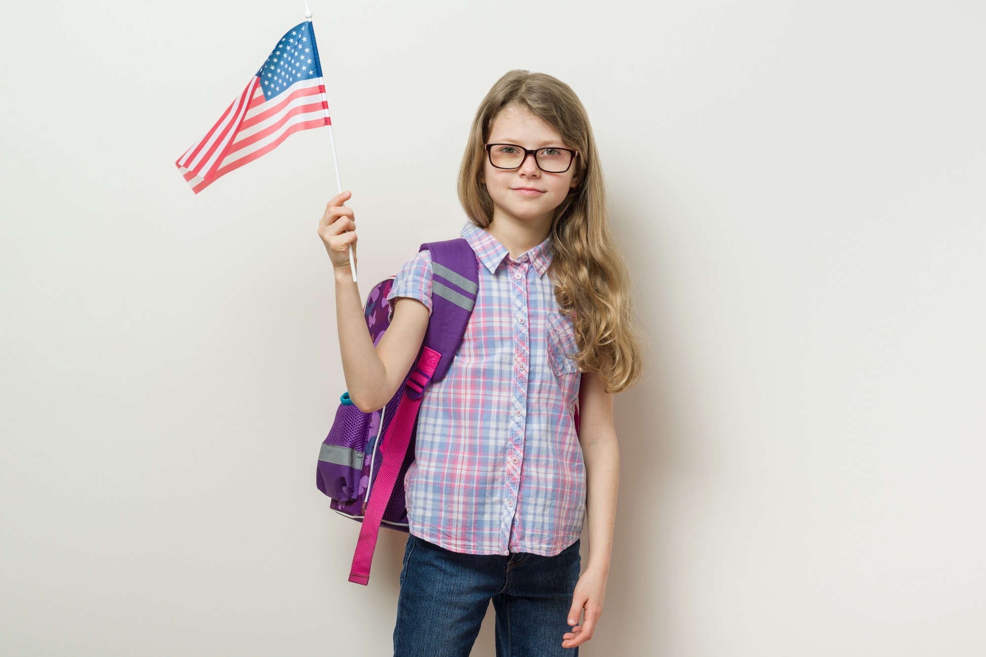 School child with a backpack holds the US flag